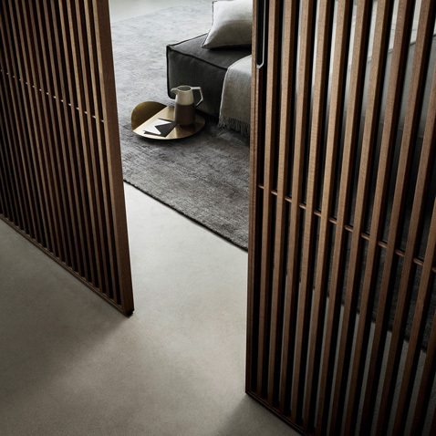 Versione in alluminio rivestito in essenza di noce e vetro trasparente grigio.