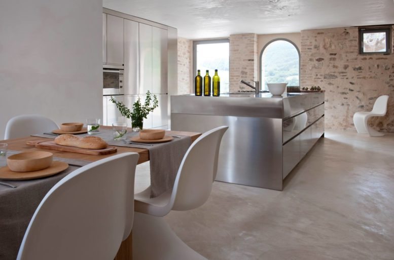 La cucina è interpretata come un ambiente aperto, libero e fruibile, pensato su misura per le esigenze dell'abitare moderno. Il piano di lavoro è funzionale a tutte le attività del contenere, preparare, cucinare e si adatta ogni giorno alle necessità dello stare insieme e del vivere la casa. Isola Convivium di Arclinea, tavolo Seven per B&B Italia di Jean Marie Massaud, sedia Papilio per B&B Italia di Naoto Fukasawa. 