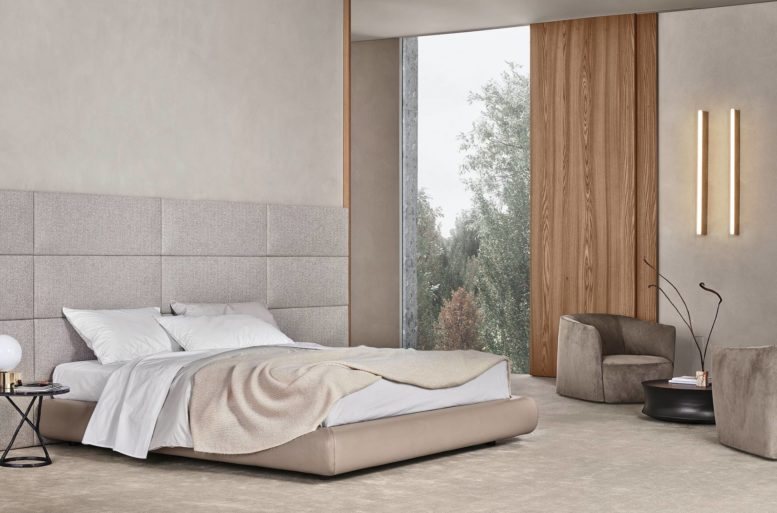 Letto Dream, design Marcel Wanders, con pannellatura a muro rivestita in tessuto sfoderabile Skyros 02 sabbia e giroletto in pelle sfoderabile Soft 2 mastice. Biancheria da letto coordinata in cotone provence 01 bianco con profilo polvere e 08 polvere con profilo bianco. Tavolino Ilda, design Jean-Marie Massaud, con struttura in fusione d’ottone bronzata e piano in lapislazzulo blu. Poltrone Santa Monica, design Jean-Marie Massaud, rivestite in pelle sfoderabile Nabuk 2 tortora. Tavolino Soori, design Soo Chan, in metallo finitura bronzo anticato.