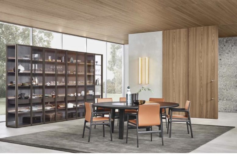 Sistema Giorno Wall System, design R&D con struttura a telaio Ego Day, ripiani in laccato opaco visone, illuminazione a led integrata. Tavolo Home Hotel, design Jean Marie Massaud in olmo nero con piano centrale girevole, integrato in marmo. Sedie Ipanema con braccioli e rivestimento in pelle. Tappeto Plain tortora.