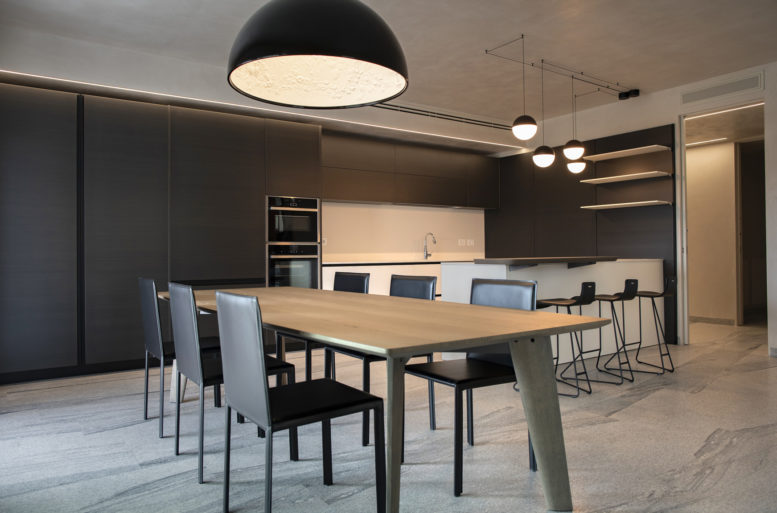 Private kitchen for family use. The bronze doors are in contrast with the more operational white part. The refined Varenna kitchen by Poliform still leaves room for the second protagonist of this environment: lighting. Bright paths on the counter and on the snack and the large lamp with bas-relief on the dining table.