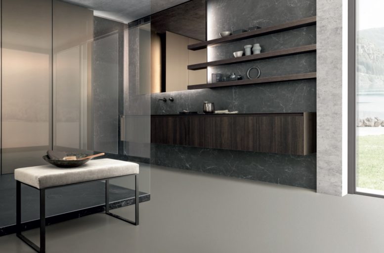 SKILL
Skill è una nuova proposta nell’ambiente bagno Modulnova. Il top e i fianchi in milltech da 6 mm esprimono un design dalle linee pulite. Il lavello integrato sparisce elegantemente nel piano, mentre il grande specchio retroilluminato e la boiserie in grès nero greco creano un interessante gioco di chiaroscuri.