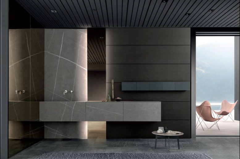 SKILL
L’utilizzo dei diversi materiali contribuisce ad evidenziare i volumi netti e proporzionati di Skill gres. Il lavabo Block sospeso in gres senda, materiale ecocompatibile, igienico e resistente, contrasta la cromia del rovere fumo della boiserie, valorizzando lo sviluppo orizzontale della composizione. Il grande specchio terra-soffitto retroilluminato esalta la texture in grès della boiserie accentuandone il sapore esclusivo. Il nuovo sistema componibile Alu box, costituito da contenitori porta oggetti in alluminio nero, aperti nella parte superiore, è un ottimo spazio di contenimento per gli accessori utilizzati nell’ambiente bagno. A completare l’attenzione e la cura del dettaglio Modulnova, la rubinetteria personalizzata in acciaio inox satinato.